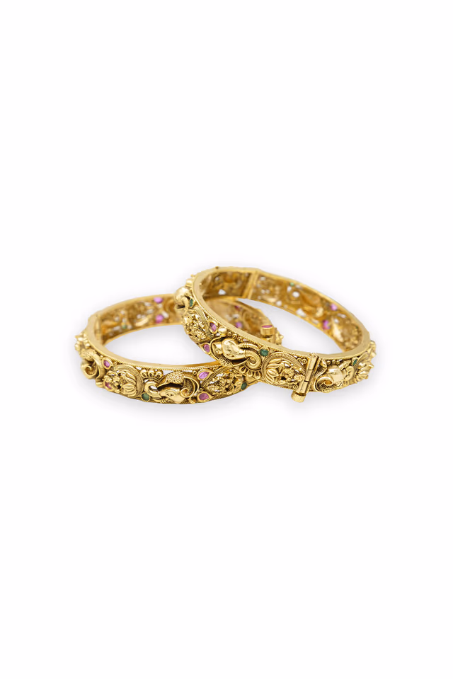 Ornate gold bangles showcase stunning ruby and emerald stones in intricate floral designs. — rent in Coimbatore